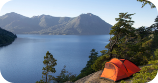 A cliffside campsite with a tent overlooking a lake